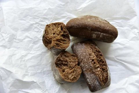 Rolls of rye black bread on white paper 스톡 사진