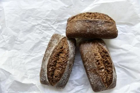 Rolls of rye black bread on white paper Stock Photos