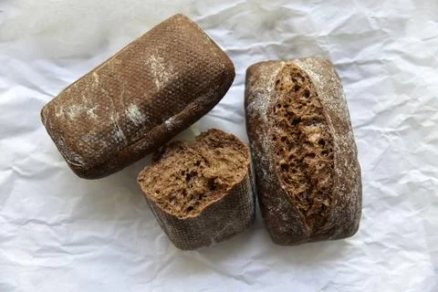 Rolls of rye black bread on white paper 스톡 사진