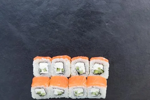 Rolls with salmon on a black stone board. Serve the dish. Rice, fish, avocado. Stock Photos