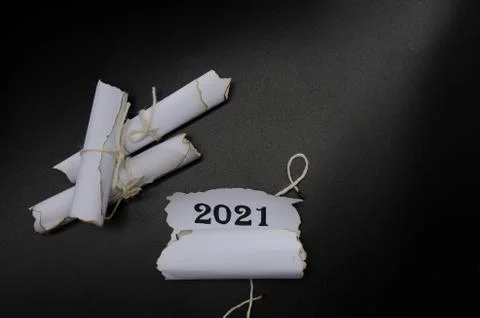 Rolls of sheets of paper on a black background. Inscription 2021 Photos
