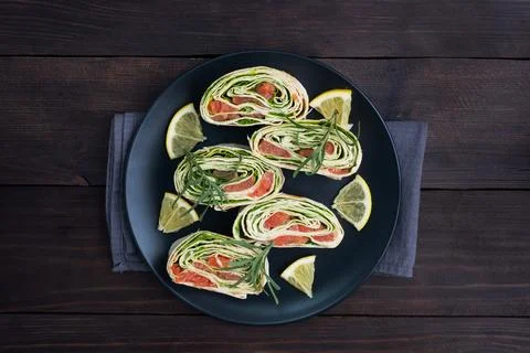 Rolls of thin pita bread and red salted salmon with lettuce leaves on a bla.. Foto stock