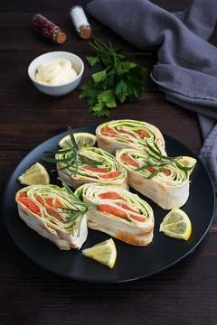 Rolls of thin pita bread and red salted salmon with lettuce leaves on a bla.. Stock Photos