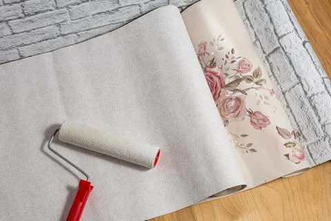 Rolls of wallpaper with a pattern and a roller are laid out on the floor and  Stock Photos