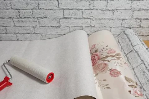 Rolls of wallpaper with a pattern and a roller are laid out on the floor and  Stock Photos