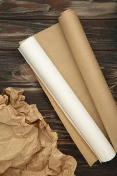 Rolls of white and brown baking paper on brown wooden background. Vertical .. Stock Photos