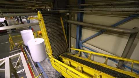 The rolls of white paper are moved along the conveyor belt to the warehouse Stockbeeldmateriaal 301557208
