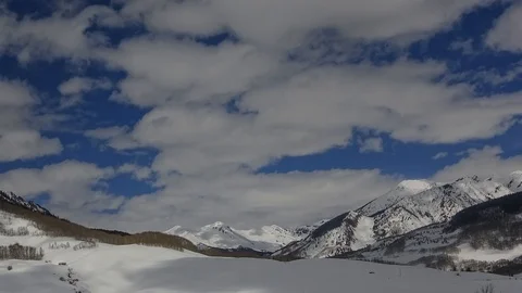 Rolly polly soft clouds flow over snow-capped peaks Stock Footage 107622116
