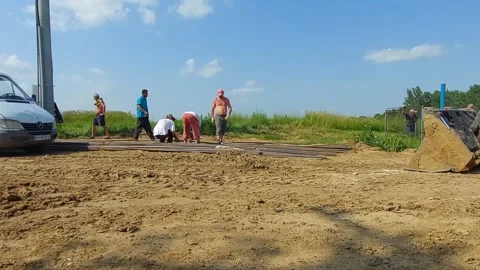 ROMAN, ROMANIA - 06/24/2021: Workers Manually Transporting Reinforcement Steel Stock Footage 156136338