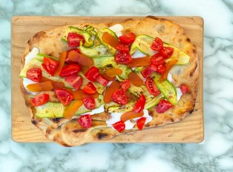Roman-style flatbread with zucchini, cherry tomatoes and bottarga Stock Photos