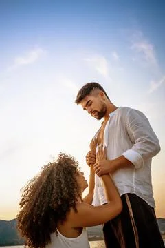 Romance scene of handsome bearded guy holding his kneeling girlfriend by the  Stock Photos