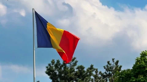 Romanian flag waving in wind against blue sky with white clouds, horizontal Stock Footage 334075589
