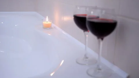 Romantic atmosphere in bathroom with two wine glasses and burning candle. Stock Footage 270539987