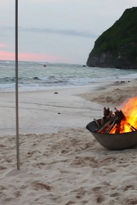 Romantic atmosphere created from a fire burning in a bowl on a paradise beach Stock Footage 275803738