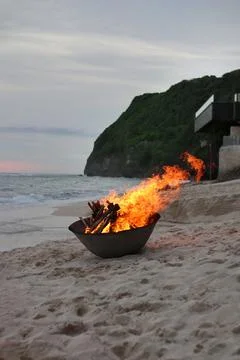 Romantic atmosphere created from a fire burning in a bowl on a paradise beach Stock Photos
