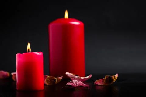Romantic background. Red candles are burning strewn with rose petals on a bla Stock Photos