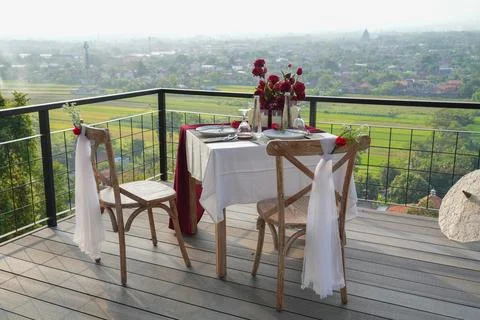 Romantic balcony dinner setup for two with a wide city and landscape view. 스톡 사진