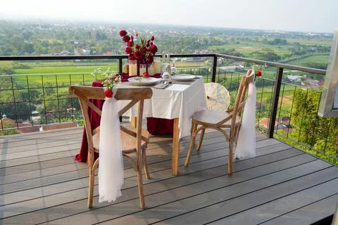 Romantic balcony dinner setup for two with a wide city and landscape view. Stock-Fotos