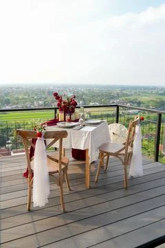 Romantic balcony dinner setup for two with a wide city and landscape view. Stock-Fotos