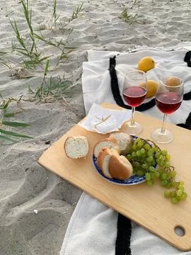 Romantic beach picnic with wine, cheese, bread, and grapes on a blanket Fotos Stock
