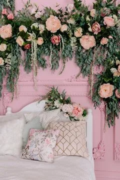 Romantic bedroom corner with a white bed, decorative pillows, and a lush floral Foto stock