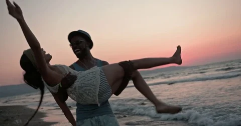Romantic boyfriend carrying and spinning girlfriend at beach at sunset Stock Footage