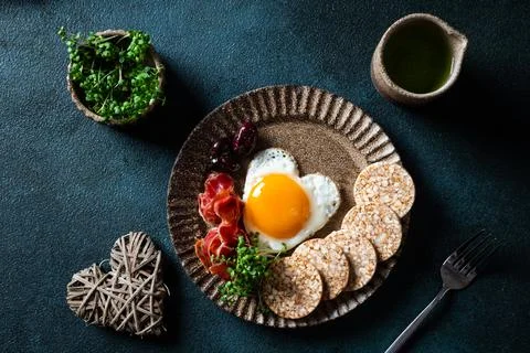 Romantic breakfast - fried eggs in the shape of a heart and olives. Healthy b Stock Photos