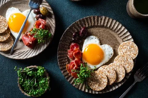 Romantic breakfast - fried eggs in the shape of a heart and olives. Healthy b Stock Photos