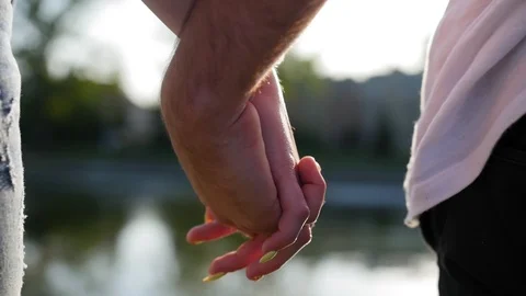 Romantic closeup of a young man`s hand holding a young woman`s hand when the Stock Footage 116686904