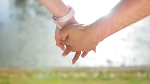 Romantic closeup of a young man`s hand holding a young woman`s hand when the Stock Footage 116687491