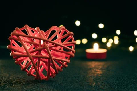 Romantic composition - one wicker heart is a symbol of love and a burning can Stock Photos