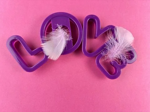 Romantic Composition of Violet Love Typography with Feathers on Pink Paper Stock Photos