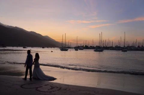 Romantic couple on the beach at sunset Stock Photos