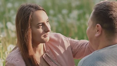 Romantic couple in the clearing among dandelions. They sit and look at each Stock Footage