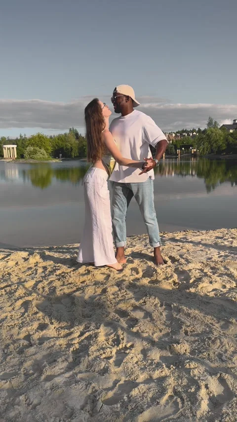 Romantic couple dancing bachata on sandy beach by lake at sunset. Man and woman Stock Footage 328591580