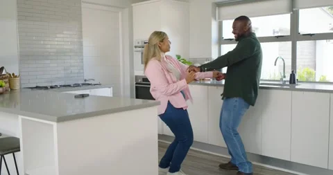 Romantic couple dancing in kitchen as man taking woman's hand by sink and Stock Footage 339321566