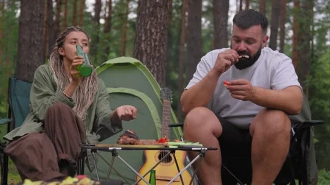 Romantic couple drinking beer and camping together in the forest Stock Footage 327529792