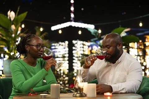 Romantic couple drinking wine during candlelit rooftop restaurant date Fotos Stock