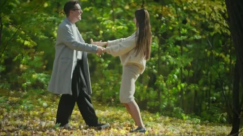 A romantic couple elegantly dancing together amidst the beautiful autumn forest Stock Footage 295230148