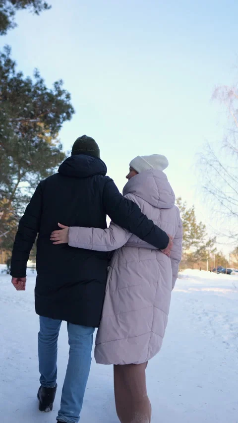 Romantic couple embracing and walking together in a snowy winter park Vidéo 330109688