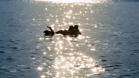 Romantic couple embracing on inflatable ring at sunset Stockbeeldmateriaal 316349970