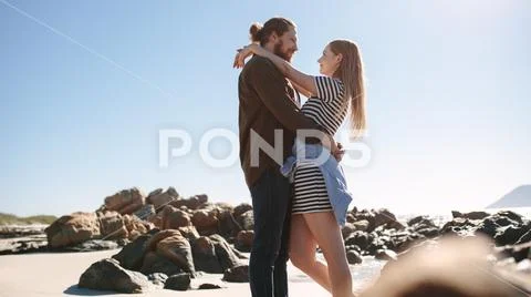 Romantic Couple Embracing On The Rocky Beach