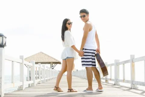 Romantic couple holding hand while walk along bridge pier Stock Photos
