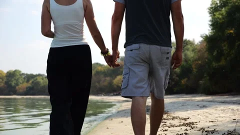 Romantic couple holding hands of each other and walking at coastline. Happy pair Vídeo Stock 344041233