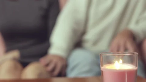 Romantic couple holding hands on sofa, soft pink candlelight casting warm s.. Stock Footage 300588103