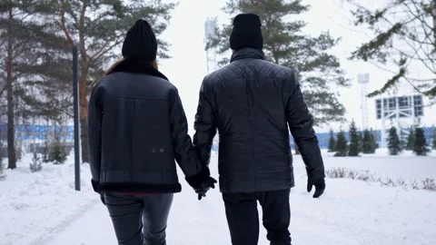 Romantic couple holding hands walking in a snowy winter park 스톡 동영상 330106007