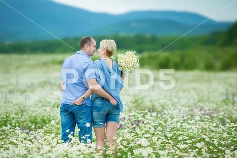 Romantic couple hugging and breathing fresh air in a warm field with daizy fl Stock Photos