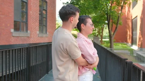 Romantic couple hugging on bridge by brick building Stock Footage 329397924