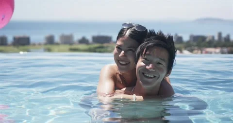 Romantic couple hugging in infinity pool on vacation, woman wrapping arms around Stock Footage 335365778
