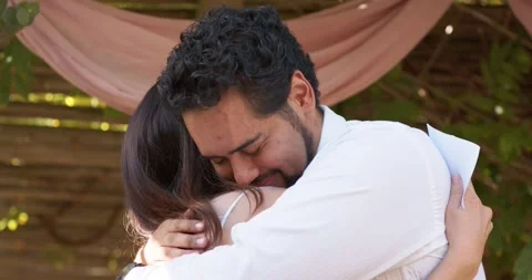 Romantic couple hugging under pink pergola drape man in white top holding folded Stock Footage 337540861